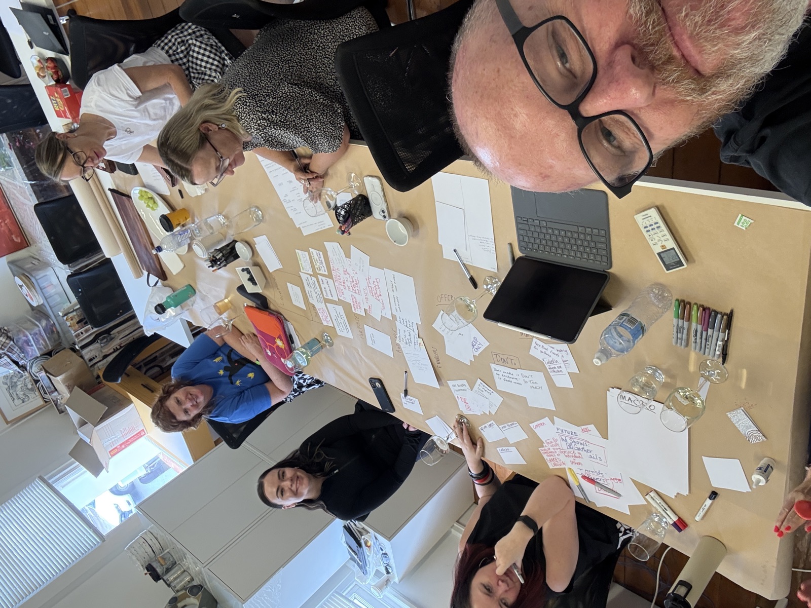 A creative-business workshop at the studio: butcher's paper notes, sticky labels and a tablet laid across the workshop table mid-strategy
